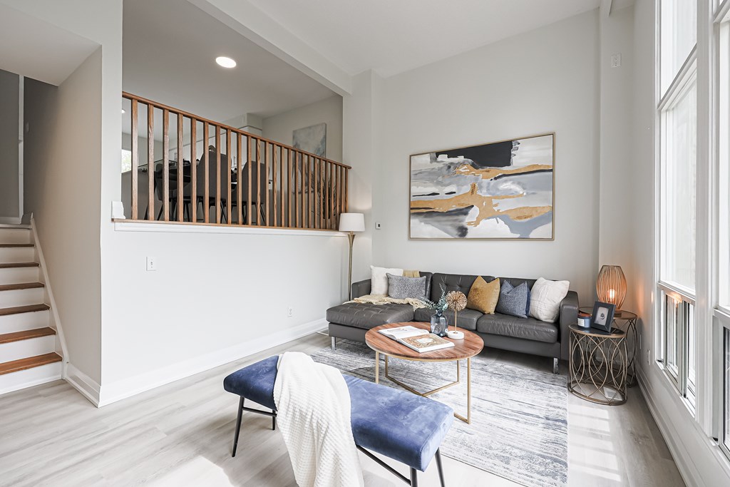A living room with a blue chair and a painting on the wall.