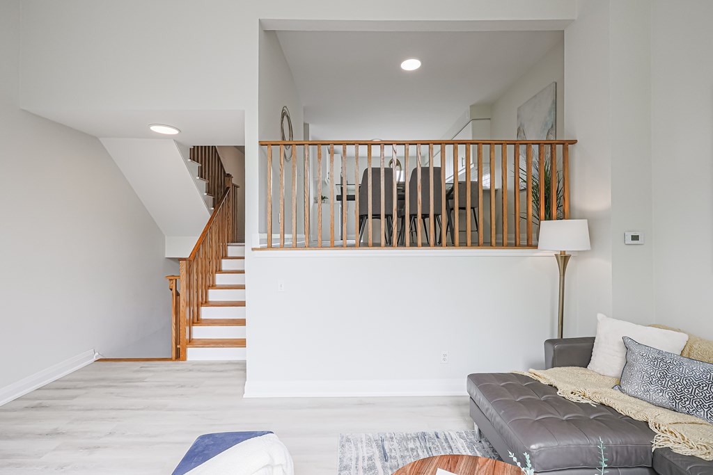 A living room with a grey couch and a staircase.