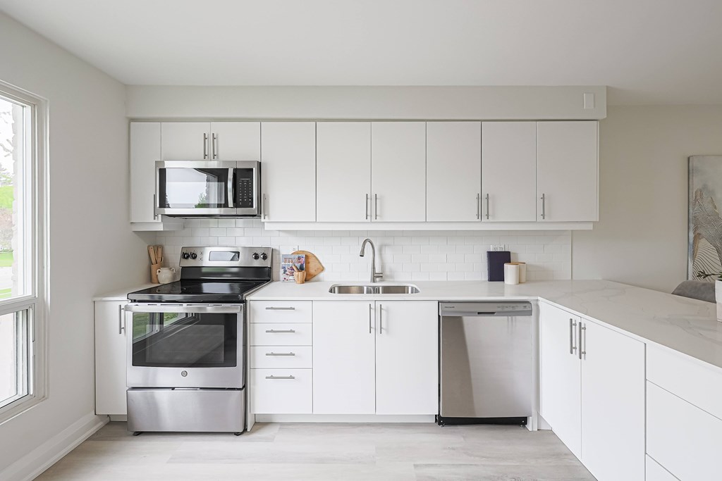 A modern kitchen with white cabinets and stainless steel appliances.