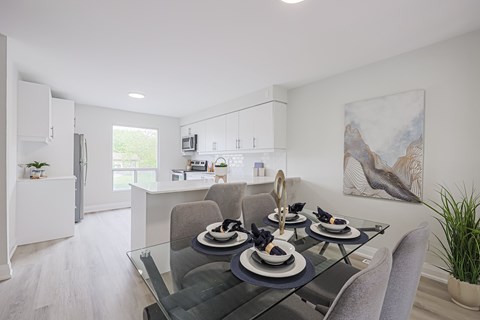 A modern dining room with a glass table and grey chairs.