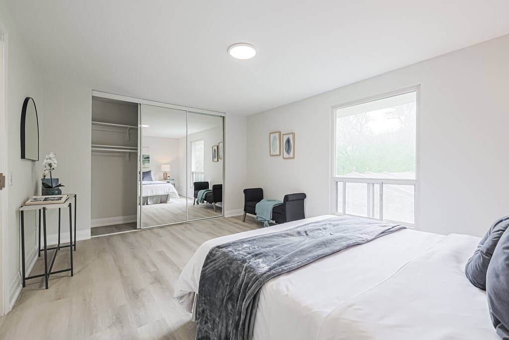 A bedroom with a large bed and a mirrored closet door.