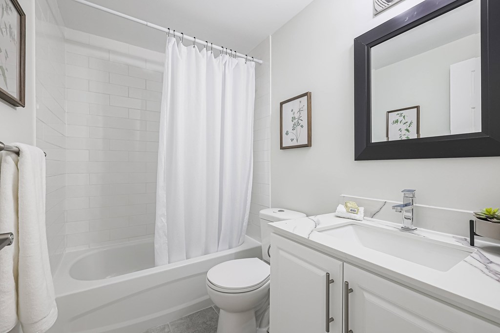 A white bathroom with a toilet, sink, and bathtub.