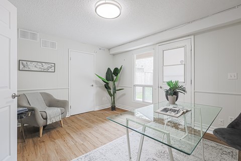 A living room with a glass table and a grey couch.