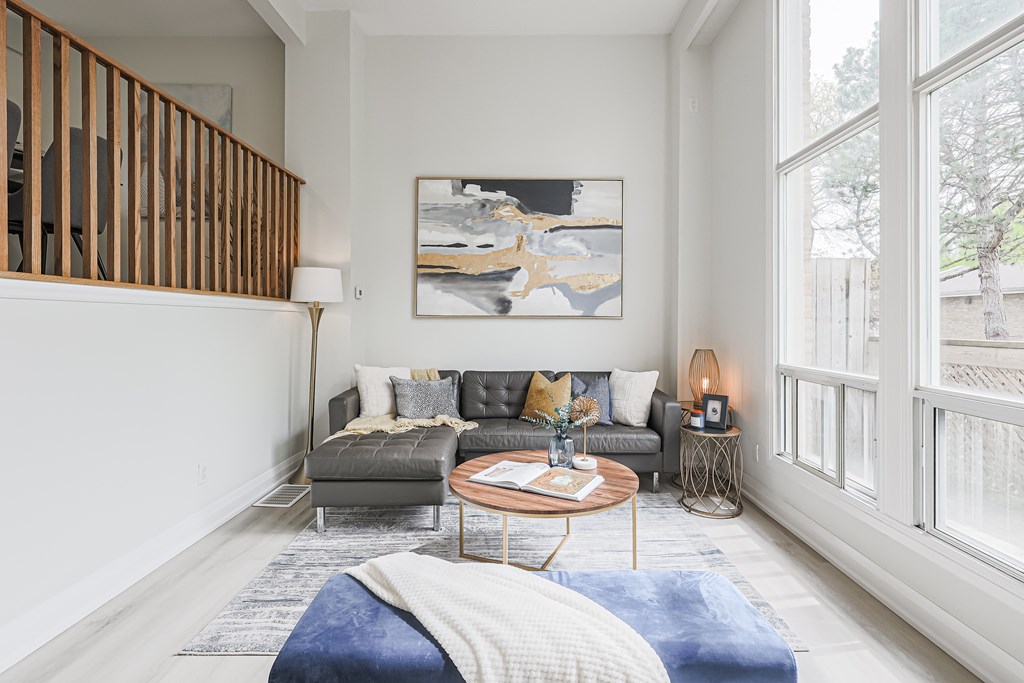 A living room with a grey couch, a coffee table, and a painting on the wall.