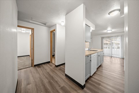 A kitchen with white cabinets and a wooden floor.