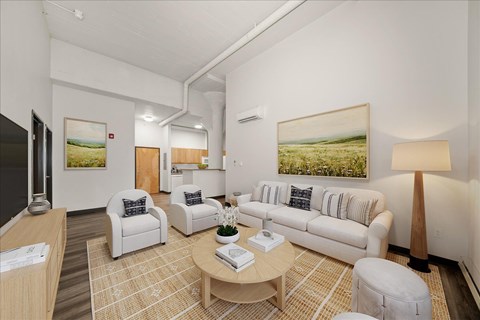 A living room with a white couch and a painting of a field on the wall.