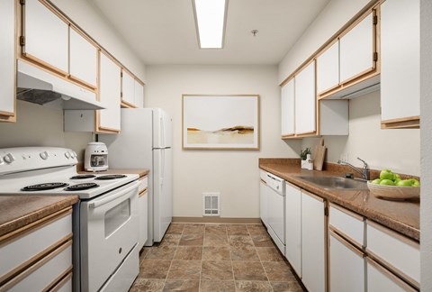 A kitchen with white cabinets and brown countertops.