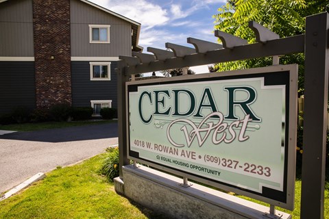 A sign for Cedar West in front of a building.