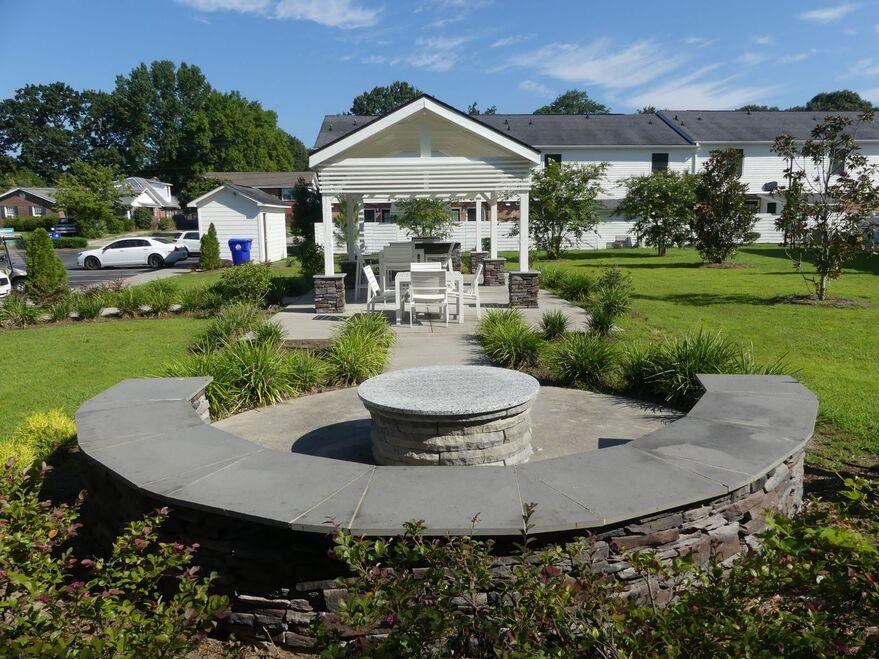 a stone fountain in a garden with a house in the background