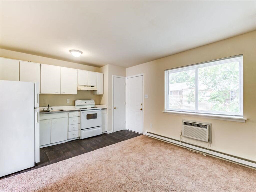 an empty kitchen with white appliances and a window