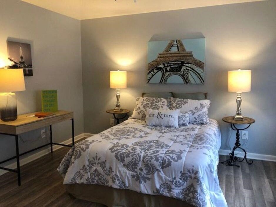 a bedroom with a bed and a painting of the eiffel tower