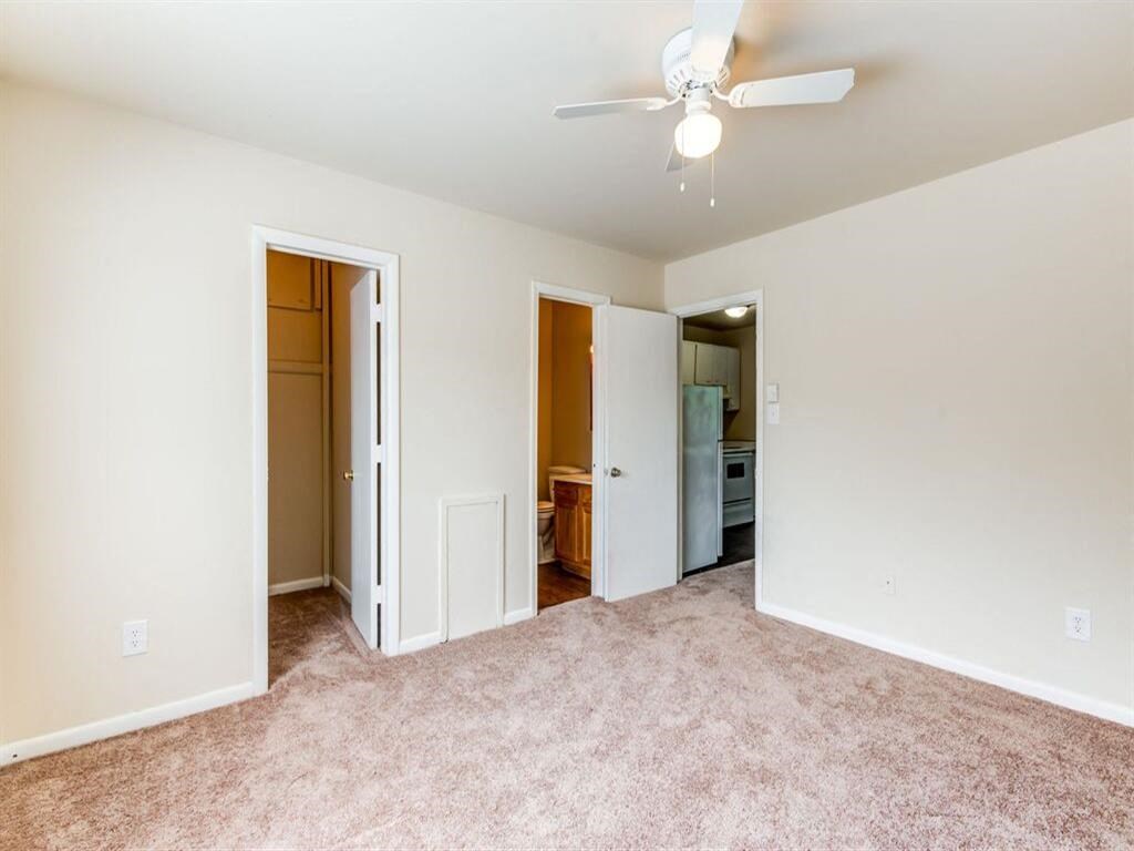 an empty living room with a ceiling fan and a closet