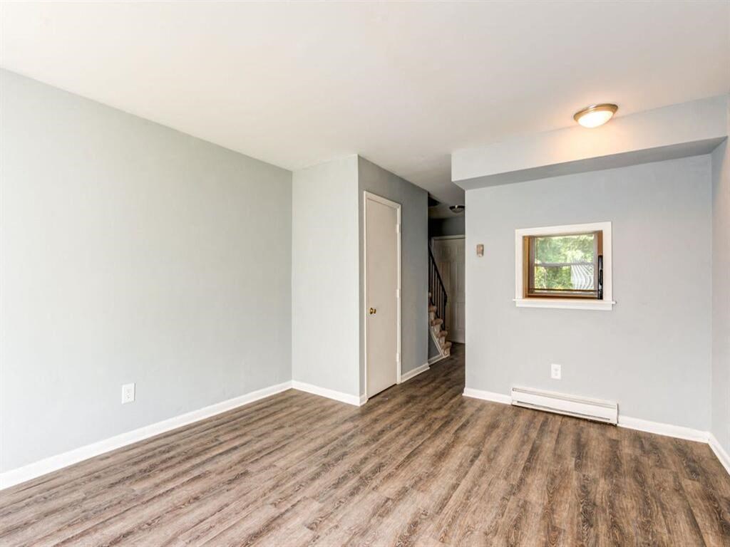 a living room with a hard wood floor and a door into a hallway