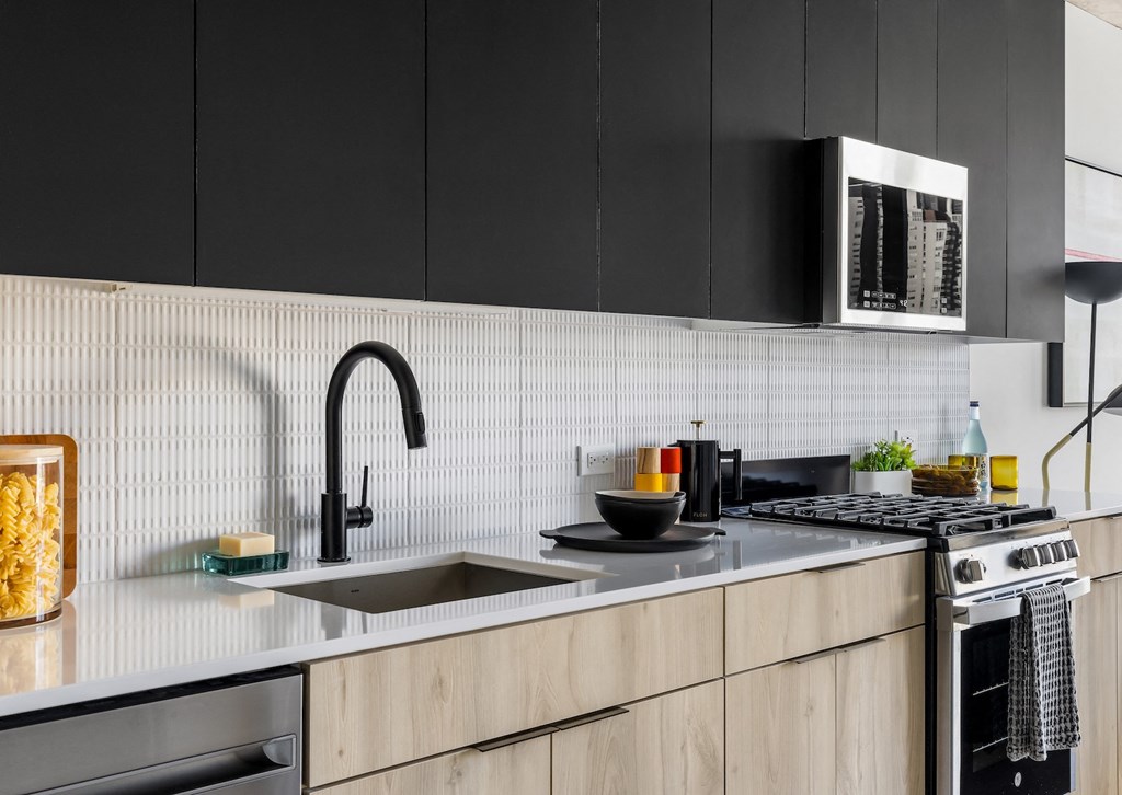 a kitchen with a sink and a stove and black cabinets