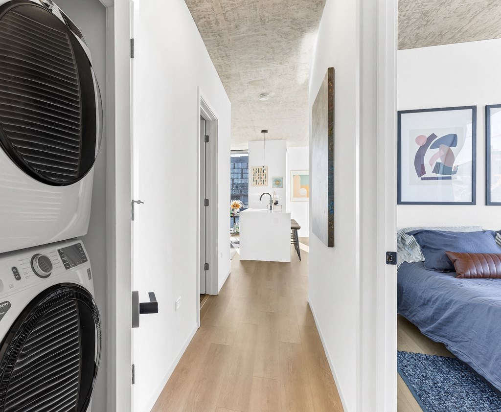 a bedroom with a washer and dryer and a hallway with a bed