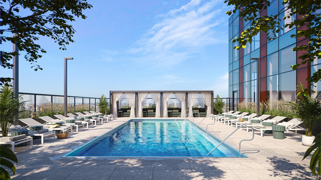 an outdoor pool with lounge chairs and a glass walled building in the background