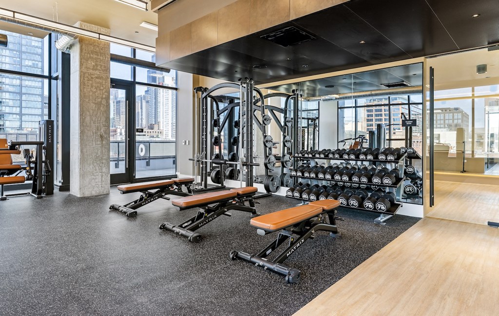 a spacious fitness center with weights and cardio equipment and glass windows