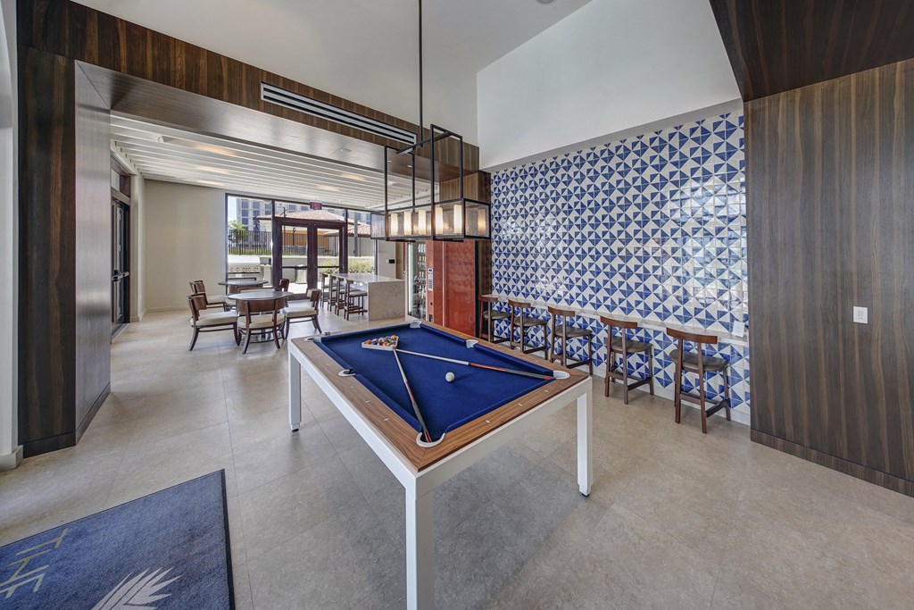 a pool table in the lobby of a hotel with tables and chairs