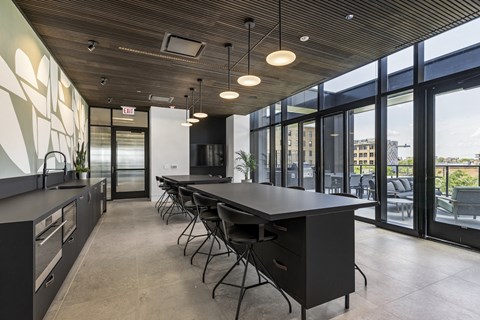 A modern kitchen with a long black table and chairs.