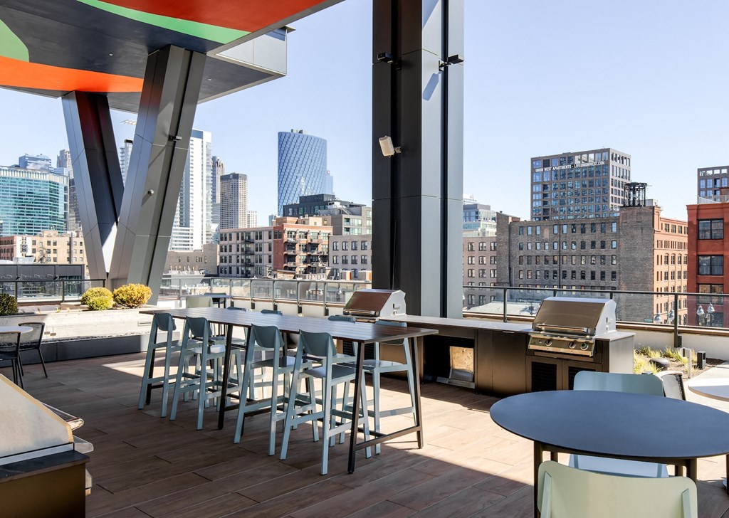 a rooftop bar with tables and chairs and a view of the city