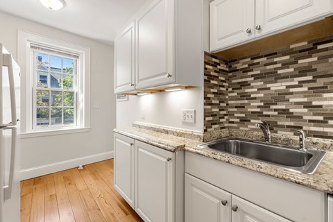 A kitchen with white cabinets and a granite countertop.