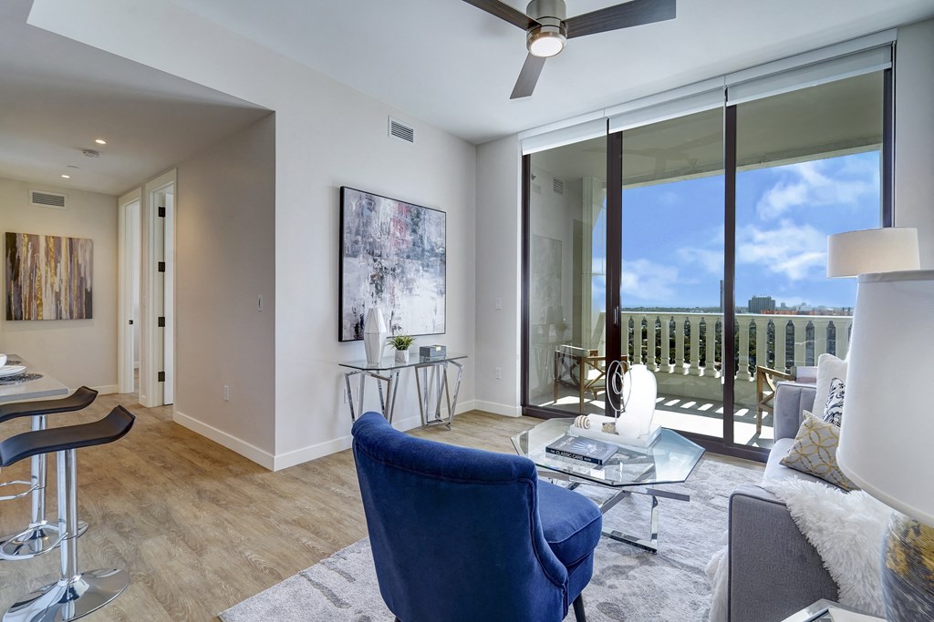a living room with a view of a balcony and a couch and chairs