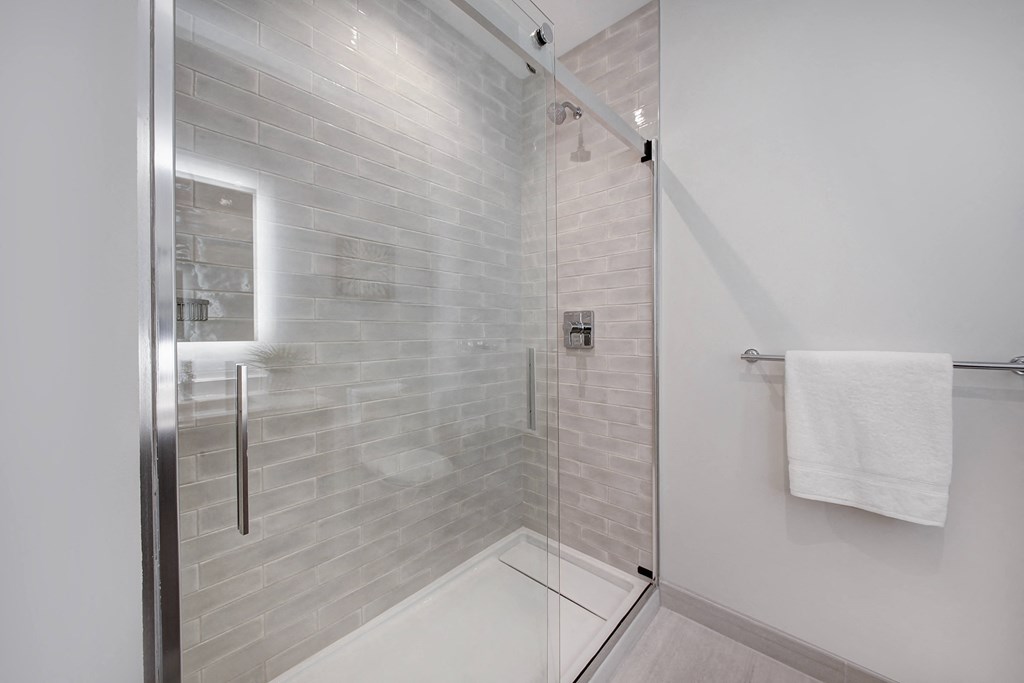 a white bathroom with a glass shower door and a white towel