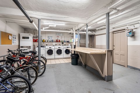 A laundry room with a washer and dryer, a table, and bicycles.
