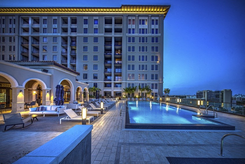 a swimming pool at night in front of a tall building