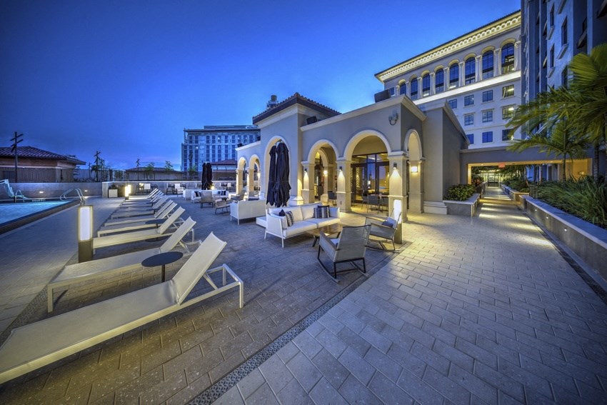a hotel patio with lounge chairs and a pool at night