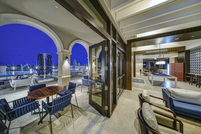 a living room with tables and chairs and a view of the ocean