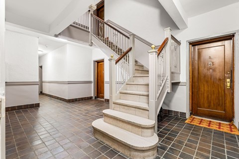 A hallway with a staircase and a wooden door.