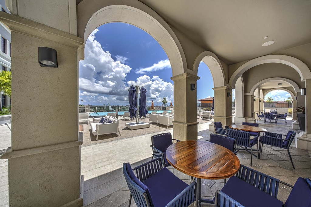 a patio with tables and chairs and a view of the ocean