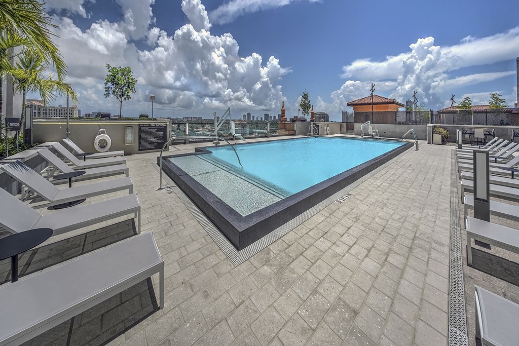 the pool on the rooftop of a building with lounge chairs and a swimming pool