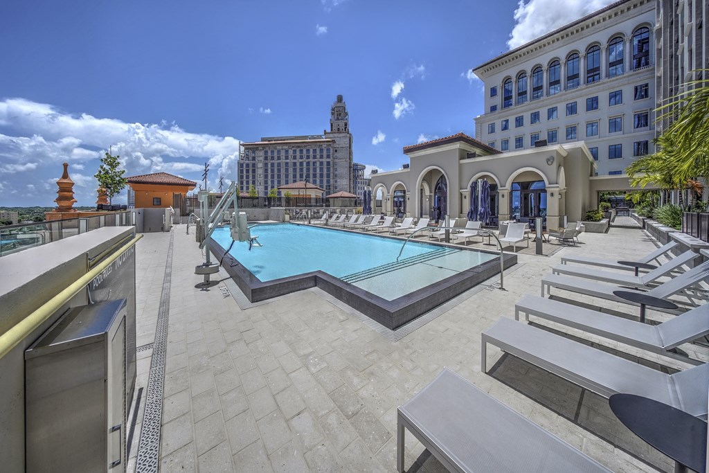 a swimming pool with lounge chairs and a building in the background