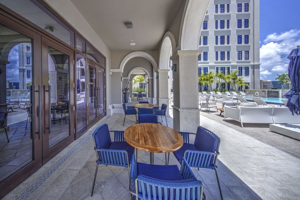 a patio with blue chairs and a wooden table