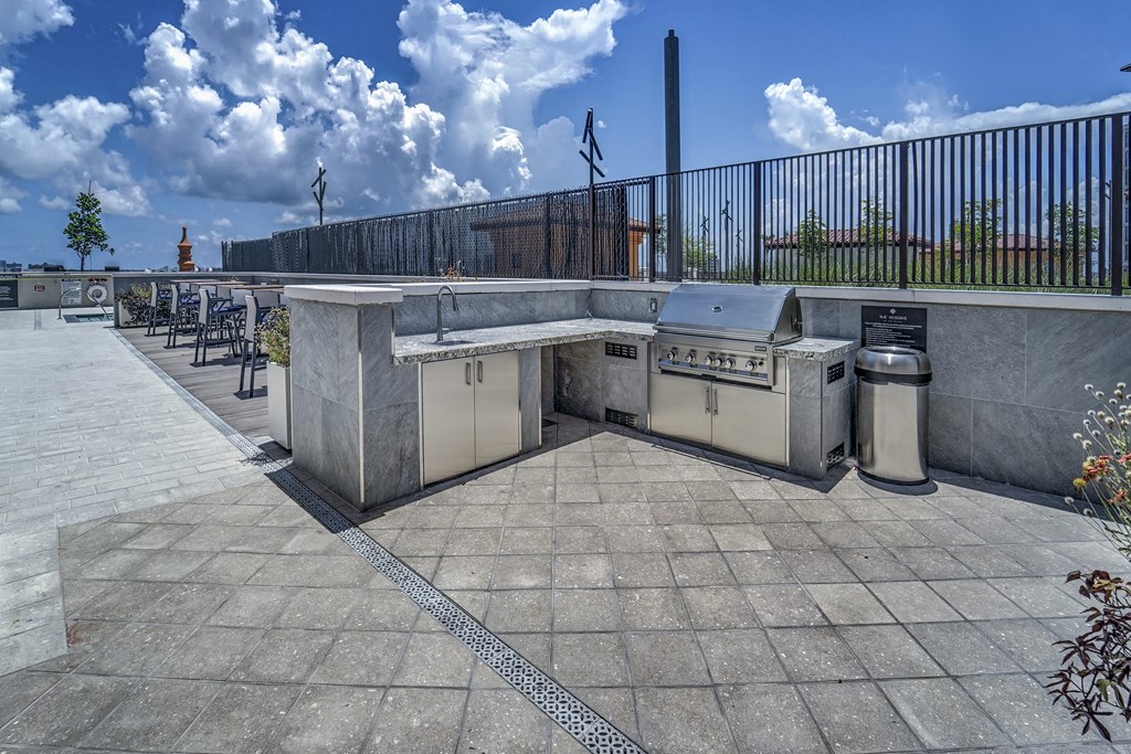 an outdoor barbecue area with two gas burners and two trash cans