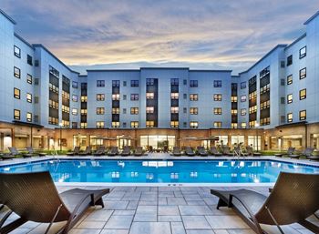 a large pool with lounge chairs and a building in the background