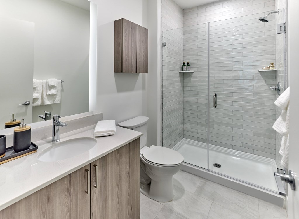A white toilet sits in a bathroom next to a sink and a walk-in shower.
