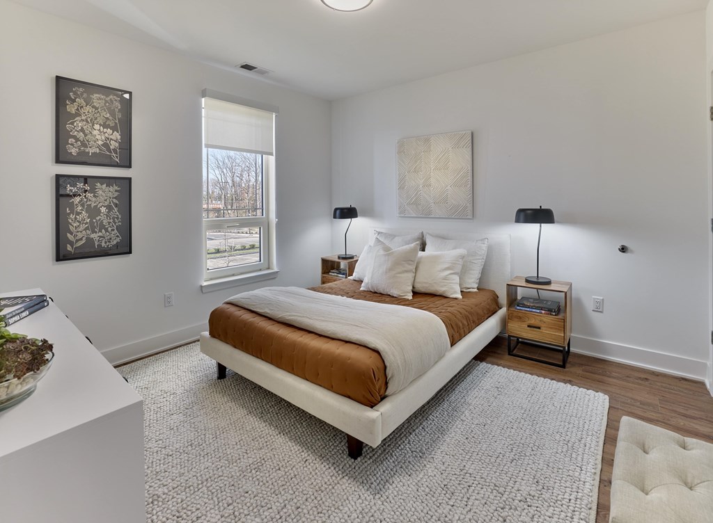 A bedroom with a bed, two lamps, and a window.