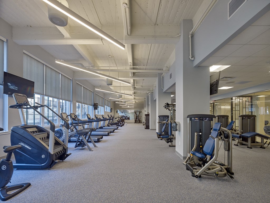 a large fitness room with cardio machines and weights