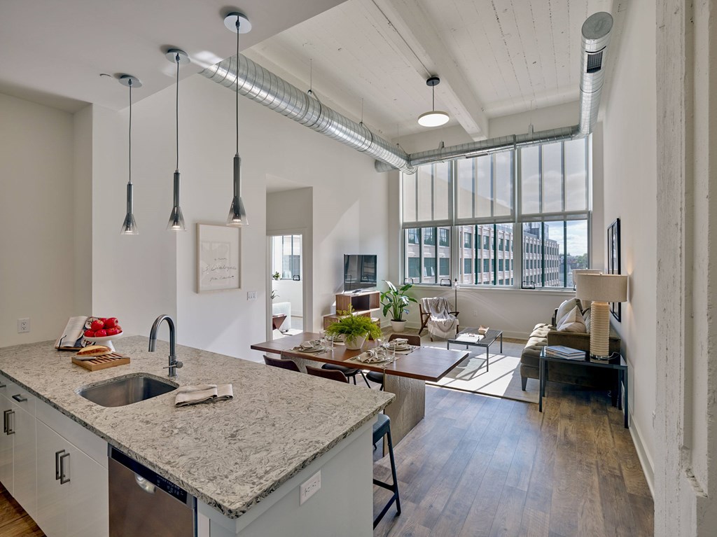 A kitchen with a granite countertop and a dining area with a couch and chairs.