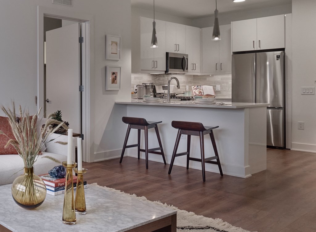 an open kitchen and living room with a bar and stools
