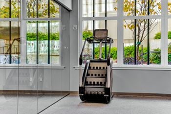A black stair climber is in front of a glass wall.