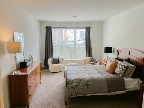 A bedroom with a large bed and a chair.