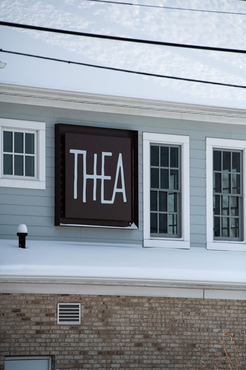 A sign with the word "THEA" is hanging on a building.