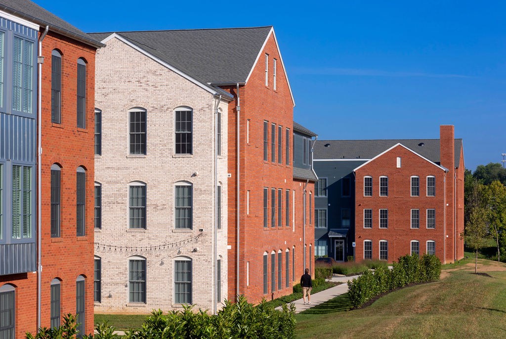 A red brick building with a black roof and a white building with a grey roof.