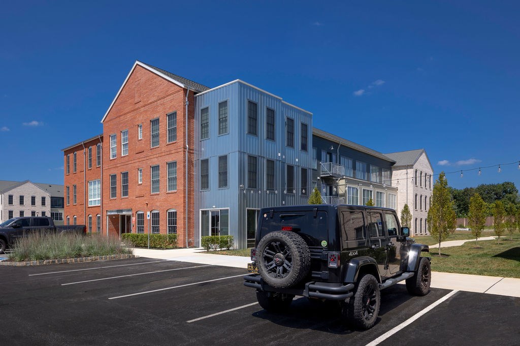 A black jeep is parked in a parking lot in front of a building.