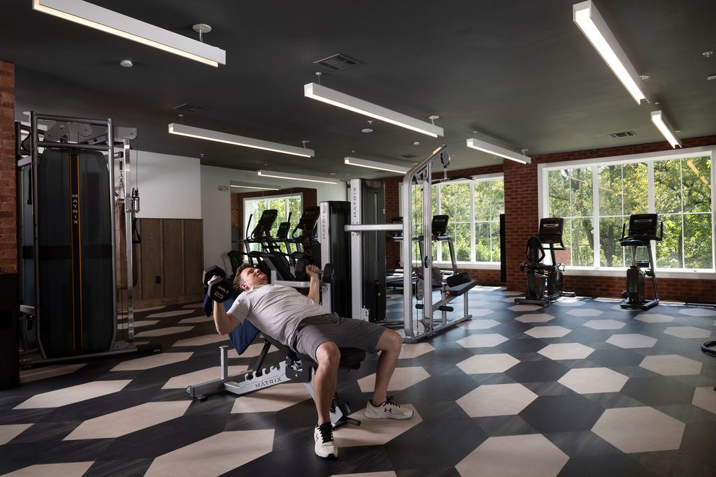 A man is working out in a gym with a checkered floor.