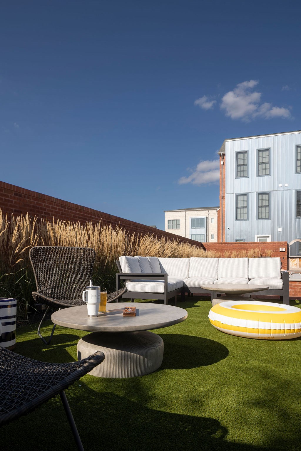 A patio with a table, chairs, and a couch with a building in the background.